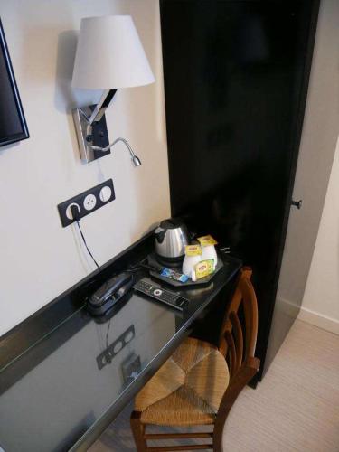 une pièce avec un bureau avec une lampe et une chaise dans l'établissement Bonséjour Montmartre, à Paris