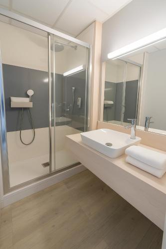 a bathroom with a sink and a shower at Logis Hotel L'Embarcadère in Nantua