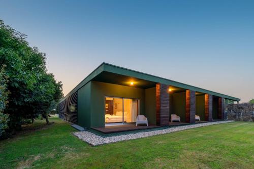 a green house with two white chairs in a yard at Stars View by Portugal Active in Fafe