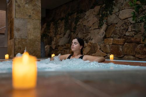 a woman sitting in a bath tub with a candle at Hotel Alba Seleqtta in Lloret de Mar