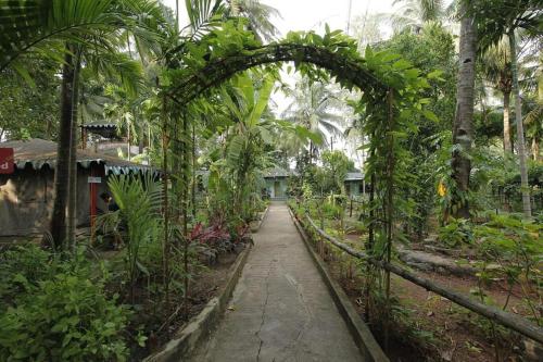 ein Torbogen in der Mitte eines Gartens in der Unterkunft Kalyani Village Resort in Khanivde