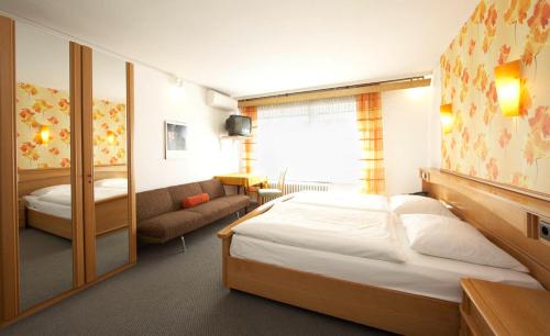 a bedroom with a large bed and a couch at Hotel Erbprinzenhof in Karlsruhe
