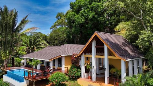 a house with a pool in front of it at Relax At This Hillside Retreat That Overlooks The Lush Forest And The Caribbean, in West End