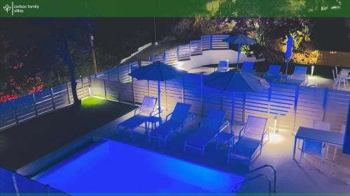a pool with chairs and tables and umbrellas at night at Zorbas Family Villas in Skiathos Town