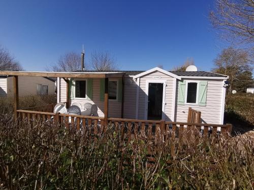 a small white house with a wooden porch at Mobilhome 6P 3CH Nature & Sport - Ivry-La-Bataille - Séjour Normandie in Ivry-la-Bataille