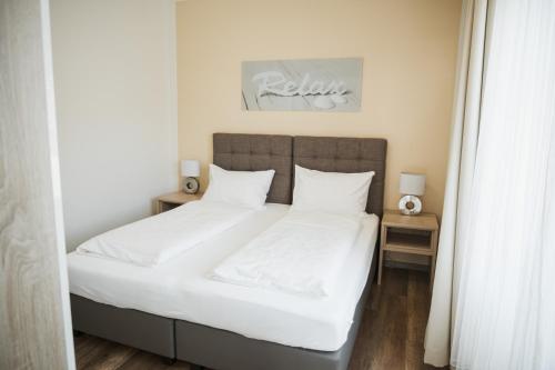 a bedroom with a bed with white sheets and pillows at R&R Residenzen Ferienwohnungen in Mitterbach
