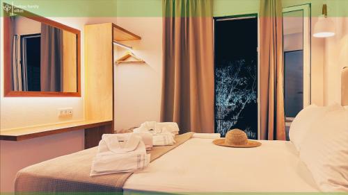 a bedroom with a bed with towels and a mirror at Zorbas Family Villas in Skiathos Town