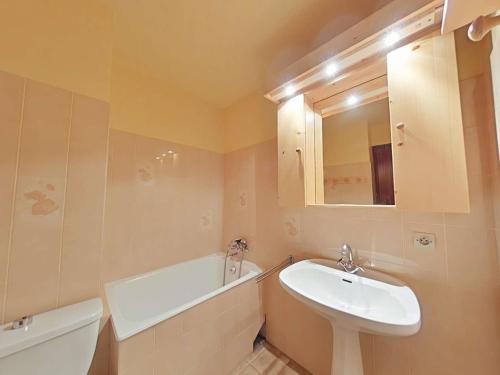 La salle de bains est pourvue d'un lavabo, de toilettes, d'une baignoire et d'un miroir. dans l'établissement Studio skis aux pieds avec balcon au Grand-Bornand - FR-1-241-20, au Grand-Bornand