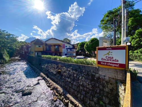a sign on a stone wall next to a river at Hotel Casa Encantada in Penedo