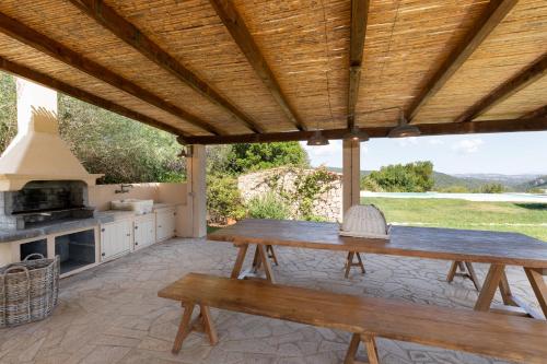 una cucina all'aperto con tavolo e panche in legno di Stazzo Spiteddu with Pool a SantʼAntonio