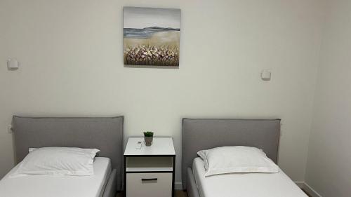 two beds in a room with a picture on the wall at MIKU Green Coast in Palasë