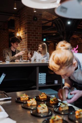 a group of people sitting at a table with plates of food at Browar Hevelius Apartments by Grand Apartments in Gdańsk