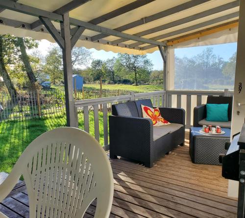 a deck with chairs and a couch and a table at Mobilhome vue sur la lande in Mimizan