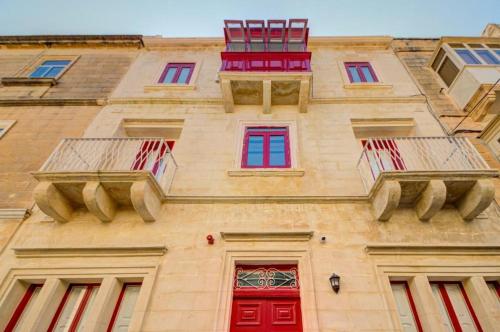 a building with red and blue doors and windows at Casa Domenico 5 in Valletta