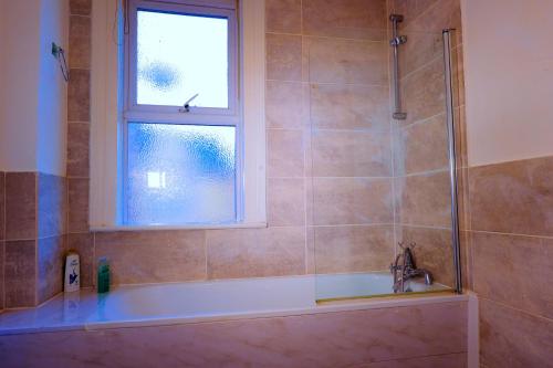 a bathroom with a bath tub and a window at Edinburgh Road Guest House in Liverpool