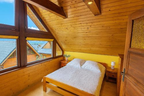 a bedroom with a bed in a wooden room with windows at BUENA VISTA POLAŃCZYK domki z klimatyzacją 506 - 289 - 019 in Polańczyk