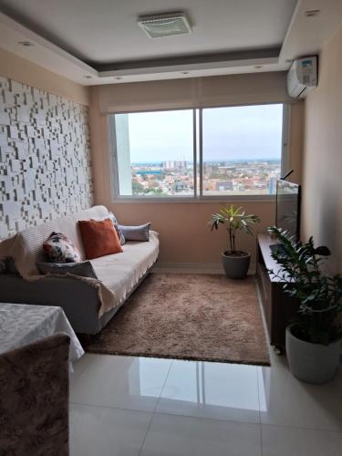 a living room with a couch and a large window at Apartamento Cond JK Parque Club in Pelotas