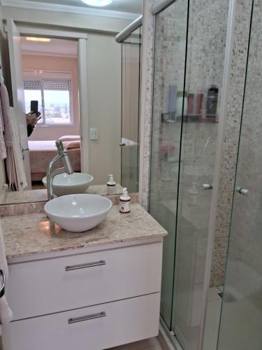 a bathroom with a sink and a glass shower at Apartamento Cond JK Parque Club in Pelotas