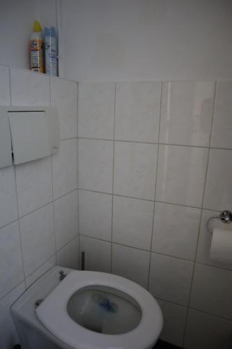 a bathroom with a toilet in a white tiled room at Kamer Joesje, Den Bosch in Den Bosch