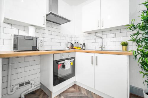 a white kitchen with white cabinets and appliances at Stylish Apartment - Wolverhampton City Centre - High-Speed Internet 12AC in Wolverhampton