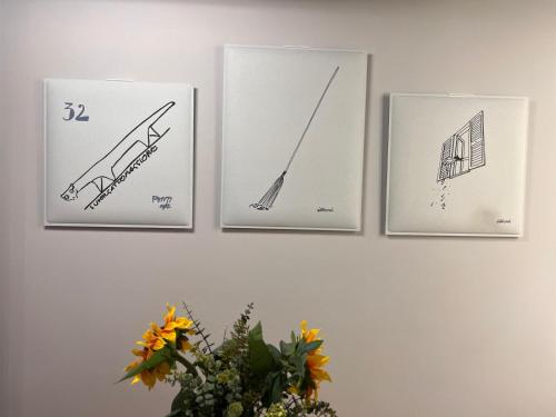 three framed drawings on a wall with a vase of flowers at Pescara INN al Golf - Jack Nicklaus in Miglianico