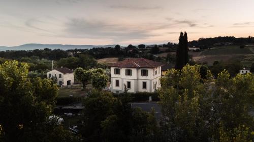 a large white house in a town with trees at Mugello Hostel in SantʼAgata