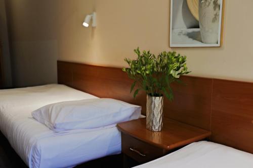 a bedroom with two beds and a vase with a plant at Hotel Victory Home in Warsaw