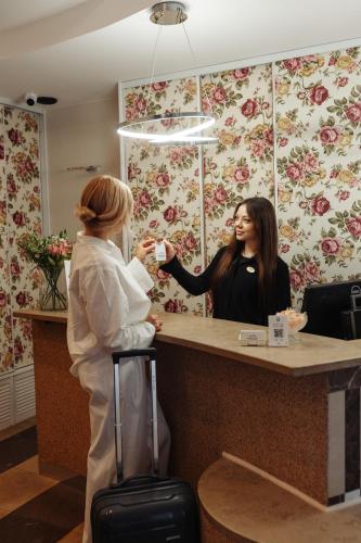 a woman standing at a counter in front of a customer at Hotel Victory Home in Warsaw