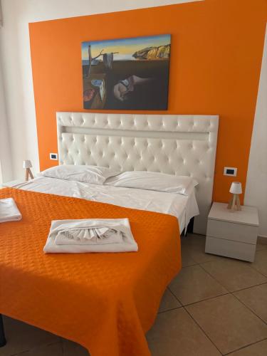 a bedroom with a white bed with an orange wall at Il dipinto in Reggio Calabria