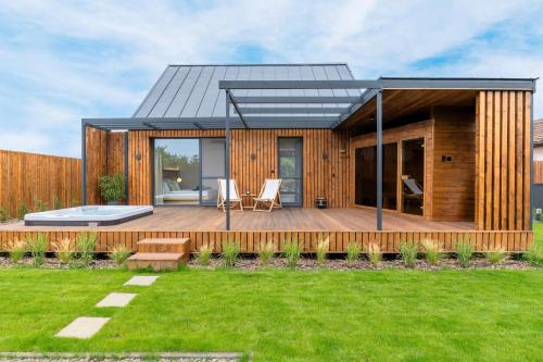 a modern house with a wooden deck and grass at Natur Harmony Tiszafüred in Tiszafüred