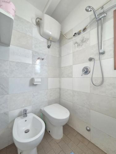 a white bathroom with a toilet and a shower at Appartamento Morelli Beach - La Baracchina sul Mare in Follonica