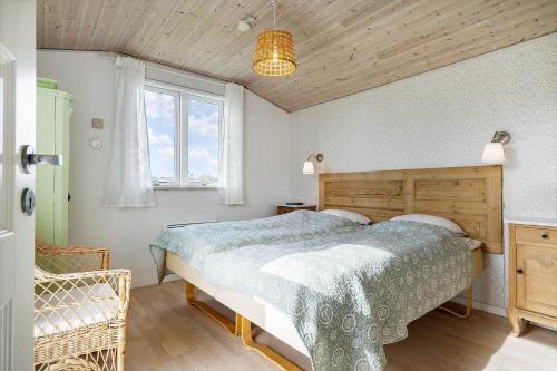 a bedroom with a bed with a wooden headboard and a window at 350-Hvide-Sande-Fyrmarken-12 in Hvide Sande