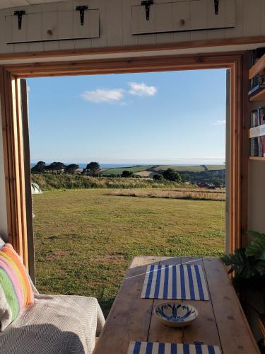 a table in front of a window with a view of a field at Monroe Horsebox Glamping in Porthleven