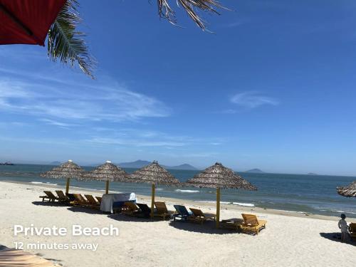 a beach with chairs and umbrellas and the ocean at Old Town Hotel in Hoi An