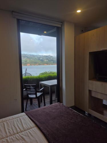 a bedroom with a large window with a view of the water at Casa el OLIVO in Club Las Anonimos