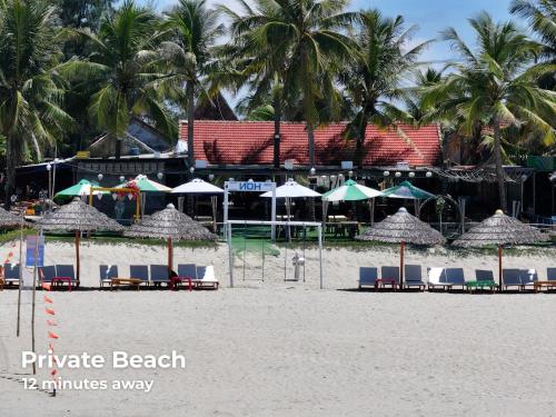 a beach with chairs and umbrellas on the sand at Old Town Hotel in Hoi An