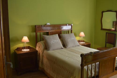uma cama num quarto verde com 2 candeeiros em Casa Rural Los Lláganos em Villaturiel