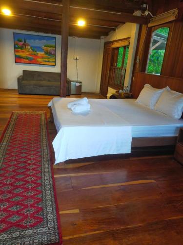 a bedroom with a large white bed and a rug at Cham Island Wooden Cabin in Hoi An