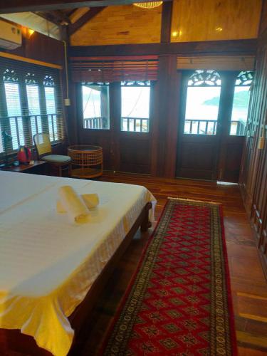 a bedroom with a bed and a rug and windows at Cham Island Wooden Cabin in Hoi An