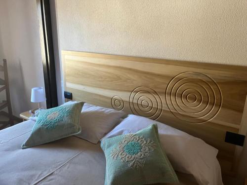 a bed with a wooden headboard and two pillows at Casa Ziranu Sa Domo e su Cantaru in Orani