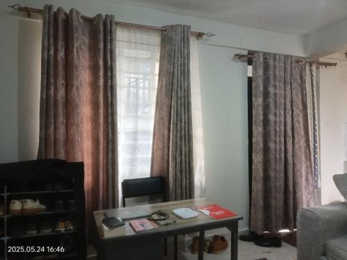 een woonkamer met een tafel voor een raam bij kire homes in Nakuru