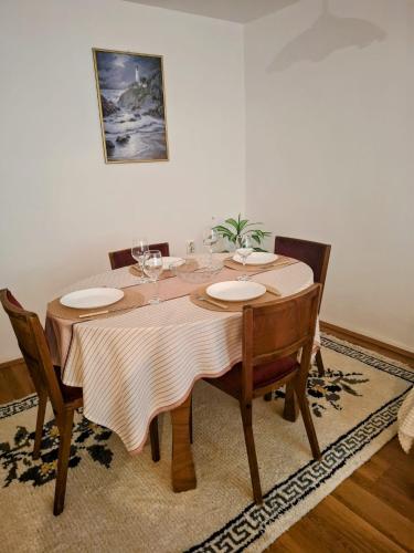a dining room table with chairs and a tablecloth at Home Well Apartman Vranje in Vranje