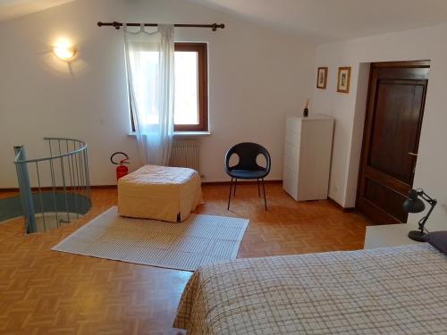 a bedroom with two beds and a chair and a window at Casa Giovanini in Cividale del Friuli
