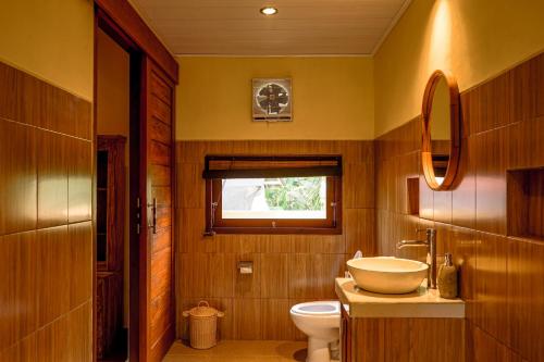 a bathroom with a toilet and a sink and a window at Uma rerama in Ubud