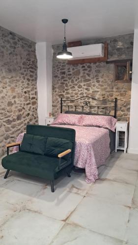 a bedroom with a bed and a stone wall at Casa Loma Lola in Molinaseca