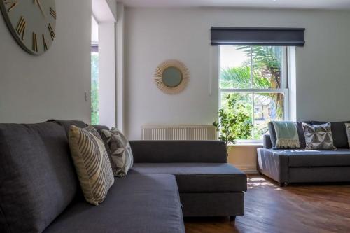 a living room with a couch and a clock on the wall at 58 Thorpe road - City Centre in Norwich