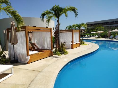 a pool at a resort with chairs and umbrellas at Hotel Mundo Maya Edzná in Nohyaxché