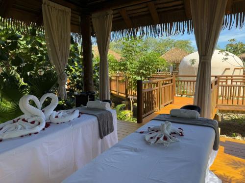 a row of beds in a pavilion with white towels at Hotel Mundo Maya Edzná in Nohyaxché