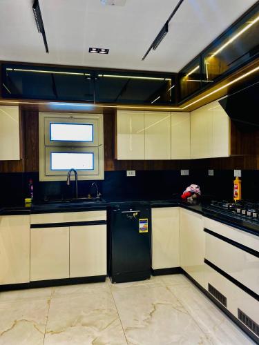 a kitchen with white cabinets and a black refrigerator at Luxury 3 bedroom apartment in Banī Ghālib