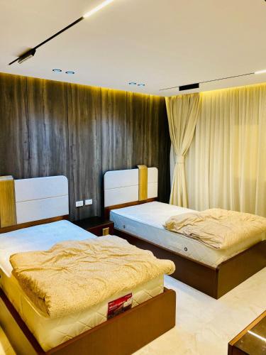 two beds sitting in a room with curtains at Luxury 3 bedroom apartment in Banī Ghālib